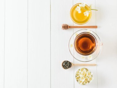 Yasemin ve çiçekler ve bal bir tablo üzerinde bir kase ile bitkisel çay. Sabah kahvaltı bileşimi. Düz yatıyordu.