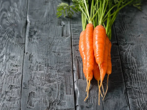 Taze havuç koyu ahşap bir masa üzerinde bir grup. Vejetaryen gıda ham doğal ürünlerle kavramı. Metin için yer.