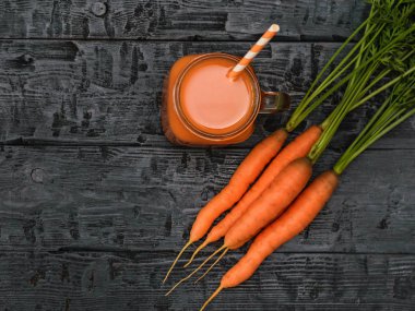 Bir fincan havuç güler yüzlü ve havuç rustik bir tabloda bir demet bir açık. Üstten görünüm. Sağlıklı beslenme kavramı. Düz yatıyordu.