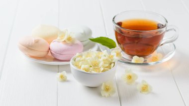 Taze çay ve bir beyaz tahta masada üç renkli şekerleme hazırlanmış. Sabah kahvaltı bileşimi. Bahar çay kompozisyon beyaz bir tablo.