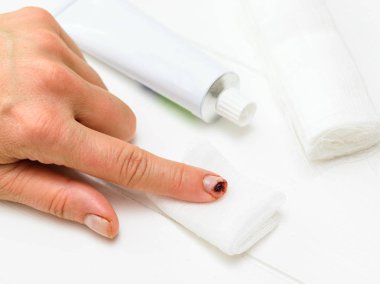 Bir bıçak kesim işaret parmağı ile sol el, bir tüp merhem ve beyaz bir tablo üzerinde bir bandaj. Bir iç durum elinde zarar.