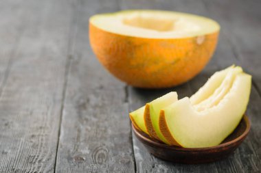 Bir kil kase ve ahşap bir masa üzerinde yarım kavun Olgun kavun parçaları. Doğal vejetaryen yemek.