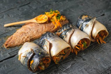 Dört uskumru sebze ve balık bir yarım karkas ile ahşap bir masa üzerinde rulo. Bir tabak deniz balık sebze ile doldurulmuş.