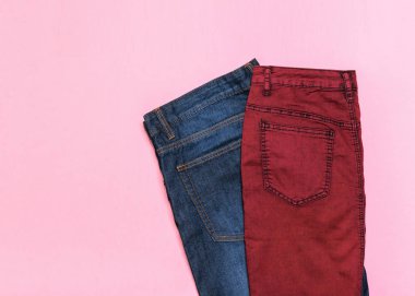 Klasik mavi erkek kot pantolon ve mor kot etek pembe bir arka plan üzerinde. Üstten görünüm. Şık denim bayanlar giyim. Denim bayanlar giyim renkli arka plan üzerinde. Düz yatıyordu.