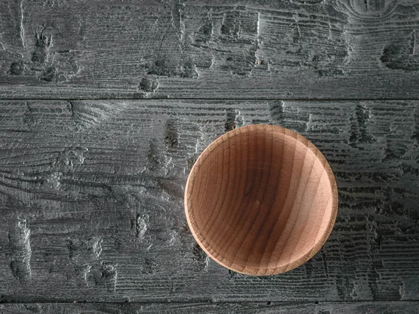Wooden bowl on the dark wooden table. Items of wooden utensils. The view from the top. Flat lay.