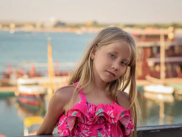 Güzel kızı Güney kentin liman arka plan üzerinde güzel bir elbise. Deniz kenarında güzel bir kızın portresi.