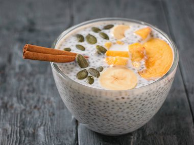 Chia tohum pudingle şeftali, kabak çekirdeği ve koyu ahşap bir masa üzerine tarçın. Diyet gıda kilo kaybı ve vücut temizliği için.