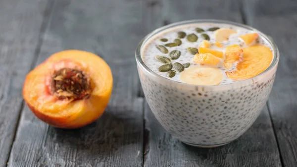 Chia seed pudding with peach and pumpkin seed on a dark wooden table. Diet food for weight loss and cleansing the body.