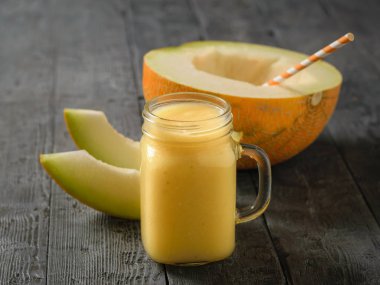 Nane ve kokteyl bir saman ve smoothies ahşap bir masa üzerinde bir kupa ile yarım kavun. Diyet İçecek meyve kilo kaybı için.