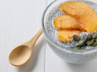 Şeftali dilimleri ile Chia puding ve kabak çekirdeği bir beyaz tahta masada. Diyet gıda kilo kaybı ve vücut temizliği için.