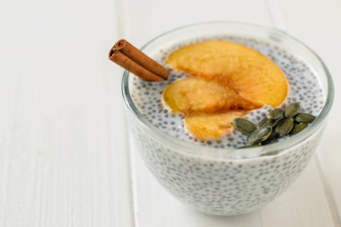 Chia tohum puding ile dilim şeftali bir beyaz tahta masada. Diyet gıda kilo kaybı ve vücut temizliği için.