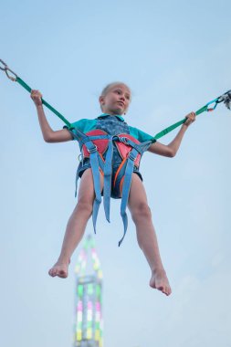 Kauçuk Kayışlar bir parlayan kule arka plan üzerinde asılı bir kız. Eğlence Parkı büyüleyici bir cazibe.