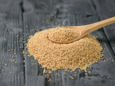 Wowooden kaşık solmayan çiçek tohumları siyah ahşap bir masa üzerinde bir yığın üzerinde. Gluten free gıda.