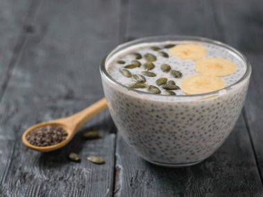 Tahta kaşıkla siyah Chia tohum ve Chia tohum puding süt siyah tablosundaki ile. Diyet gıda kilo kaybı ve vücut temizliği için.