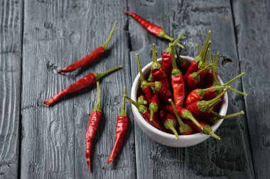 Siyah ahşap bir masa üzerinde beyaz bir kase biber kabukları. Çok amaçlı baharat. Vejetaryen mutfağı. Üstten görünüm.