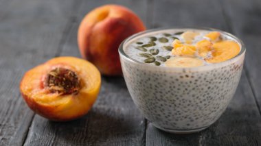 Olgun Şeftali meyve ve koyu ahşap bir masa üzerinde Chia tohum puding. Diyet gıda kilo kaybı ve vücut temizliği için.