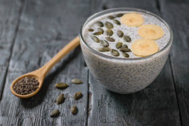 Tahta kaşıkla siyah Chia tohum ve Chia tohum puding süt siyah tablosundaki ile. Diyet gıda kilo kaybı ve vücut temizliği için.