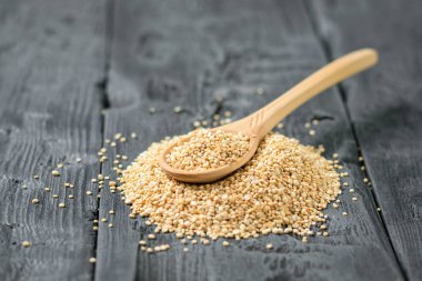 Tahta kaşık quinoa tohumlar üzerinde koyu ahşap bir masa yığını. Gluten free gıda.