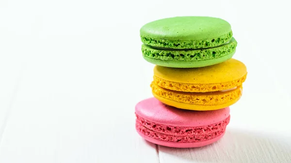 Macaroon cake red and yellow and green on a white wooden table on a white background. Freshly made homemade macaroons.