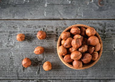 Siyah ahşap bir masa üzerinde izole fındık ile ahşap kase. Doğal Diyet vejetaryen yemek. Üstten görünüm. Düz yatıyordu.