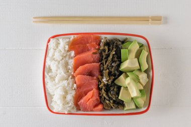 Kase uzun taneli pirinç, deniz yosunu, avokado dilimleri, bir beyaz tahta masada somon ve ahşap sopa ile. Akdeniz diyeti mutfağı. Üstten görünüm. Düz yatıyordu.