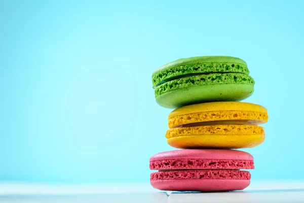 Macaroon cake red and yellow and green on a white wooden table on a blue background. Freshly made homemade macaroons.