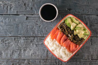Hawaii pirinç, avokado, somon ve yosun ve soya sosu siyah ahşap bir masa üzerinde bir tabak. Akdeniz diyeti mutfağı. Üstten görünüm. Düz yatıyordu.