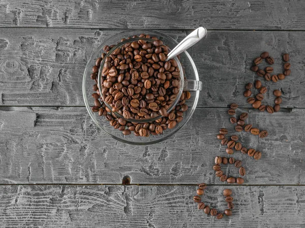Bir fincan kahve çekirdekleri ve ahşap bir masa kahve yazıt. Üstten görünüm. Taneleri popüler içki hazırlanması için.