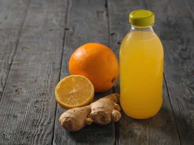 Cam şişe zencefil kökü, limon, portakal, bal ve tarçın siyah ahşap bir masa üzerinde bir içkiyle. A çare soğuk algınlığı tedavisi için ve bağışıklık sistemini güçlendirir.