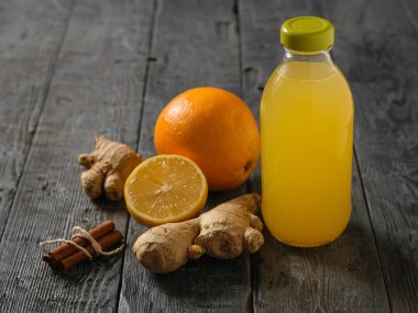 Cam şişe zencefil kökü, limon, portakal, bal ve tarçın siyah ahşap bir masa üzerinde bir içkiyle. A çare soğuk algınlığı tedavisi için ve bağışıklık sistemini güçlendirir.