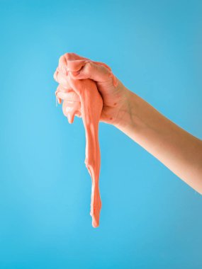 Çocuk onun sağ eli ile mavi bir arka plan üzerinde turuncu bir gülümseme dövüyor. Oyuncak antistress. El motor becerilerinin geliştirilmesi için oyuncak.