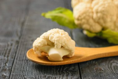 Önümüzdeki karnabahar siyah ahşap bir masa üzerinde bir tahta kaşık içinde. Sağlıklı vejetaryen diyet.