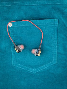 Kırmızı tel yeşil kot pantolon cebinden yapışmasını kulaklıklarla. Elektronik cihazlar için modern moda kavramı.