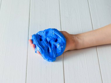 Çocuğun parmakları Beyaz ahşap bir masa üzerinde mavi bir sümük dalmış.