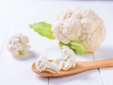 Tahta kaşık ve çiçeği beyaz bir masada karnabahar.