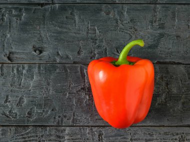 Güzel olgun kırmızı dolmalık biber siyah ahşap bir masa üzerinde. Vejetaryen yiyecekler. Üstten Görünüm. Düz yatıyordu.