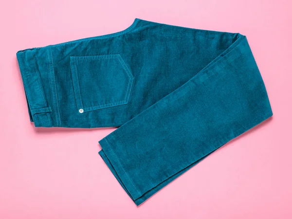 Groene vrouw jeans mooi gestapeld op een roze achtergrond. — Stockfoto