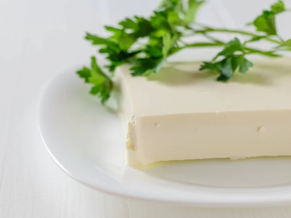 Queso serbio con hojas de perejil sobre una mesa blanca sobre un fondo blanco. La vista desde arriba. Productos lácteos . —  Fotos de Stock
