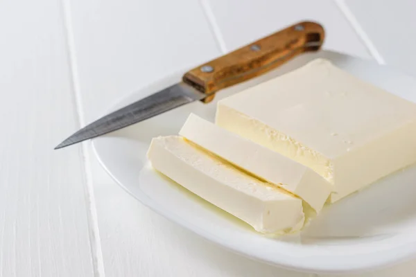 Un cuchillo con mango de madera junto a un trozo de queso serbio en rodajas. La vista desde arriba. Productos lácteos . —  Fotos de Stock