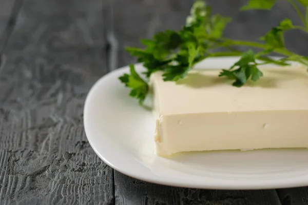 Un pedazo rectangular de queso serbio en un tazón blanco sobre una mesa de madera. La vista desde arriba. Productos lácteos . —  Fotos de Stock