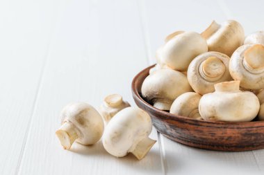 Beyaz ahşap masada mantar ile kahverengi kil kase. Vejetaryen mutfağı.