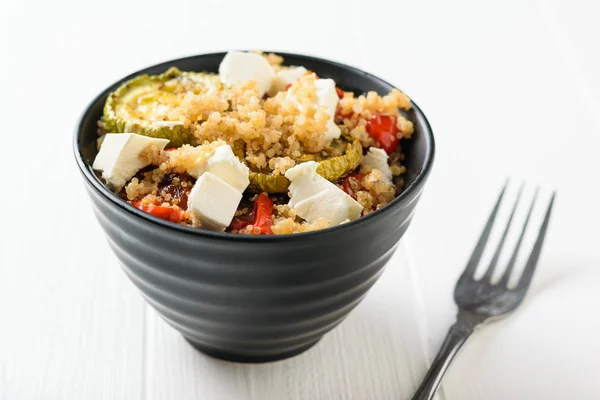 Un tenedor junto a un tazón de ensalada de quinua y verduras horneadas sobre una mesa blanca. Plato vegetariano . — Foto de Stock