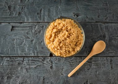 Bir kase haşlanmış Quinoa ve siyah bir masada bir kaşık. Üstteki görünüm. Düz yatma.