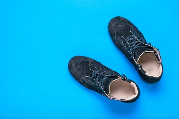 Black suede sports shoes with a blue background. The view from the top. Fashionable conception.