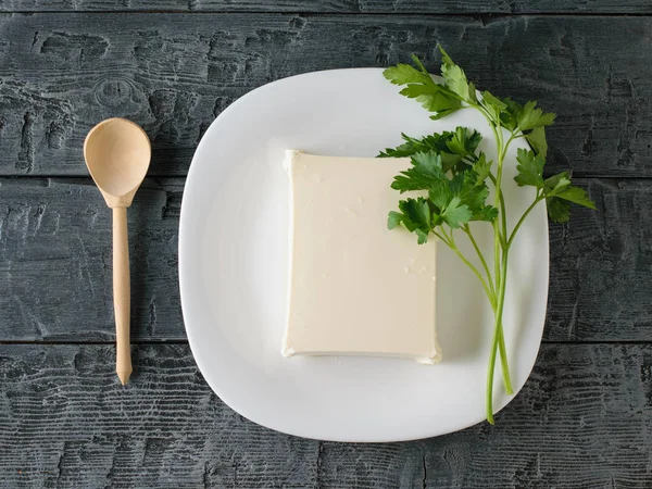 Un morceau de fromage serbe avec du persil et une cuillère en bois sur une table noire. La vue du haut. Produits laitiers . — Photo
