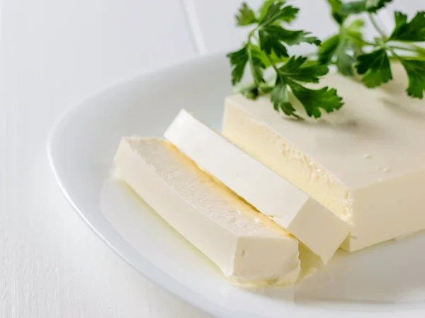 Fromage serbe au persil sur une assiette blanche sur une table blanche. La vue du haut. Produits laitiers . — Photo