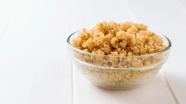 Cuenco de vidrio con quinua hervida sobre una mesa de madera blanca. Un plato de cereal hervido sin gluten . — Foto de Stock