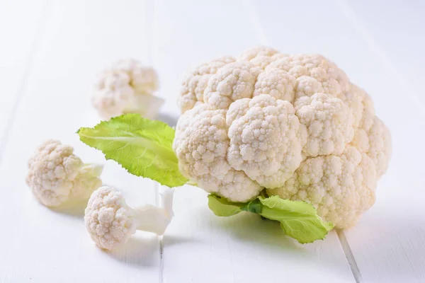 A large head of cauliflower with inflorescences on a white wooden table. — Stock Photo, Image