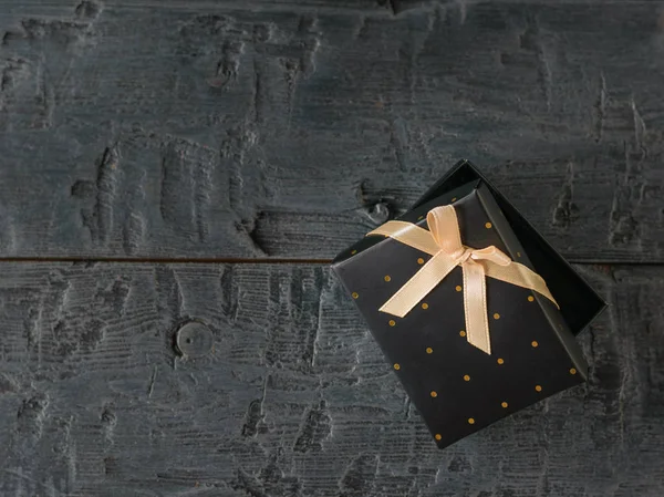 Ajar zwarte geschenkdoos met strik op houten tafel. — Stockfoto