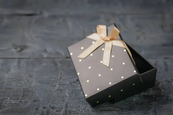 Ajar zwarte geschenkdoos met strik op een zwarte houten tafel. — Stockfoto